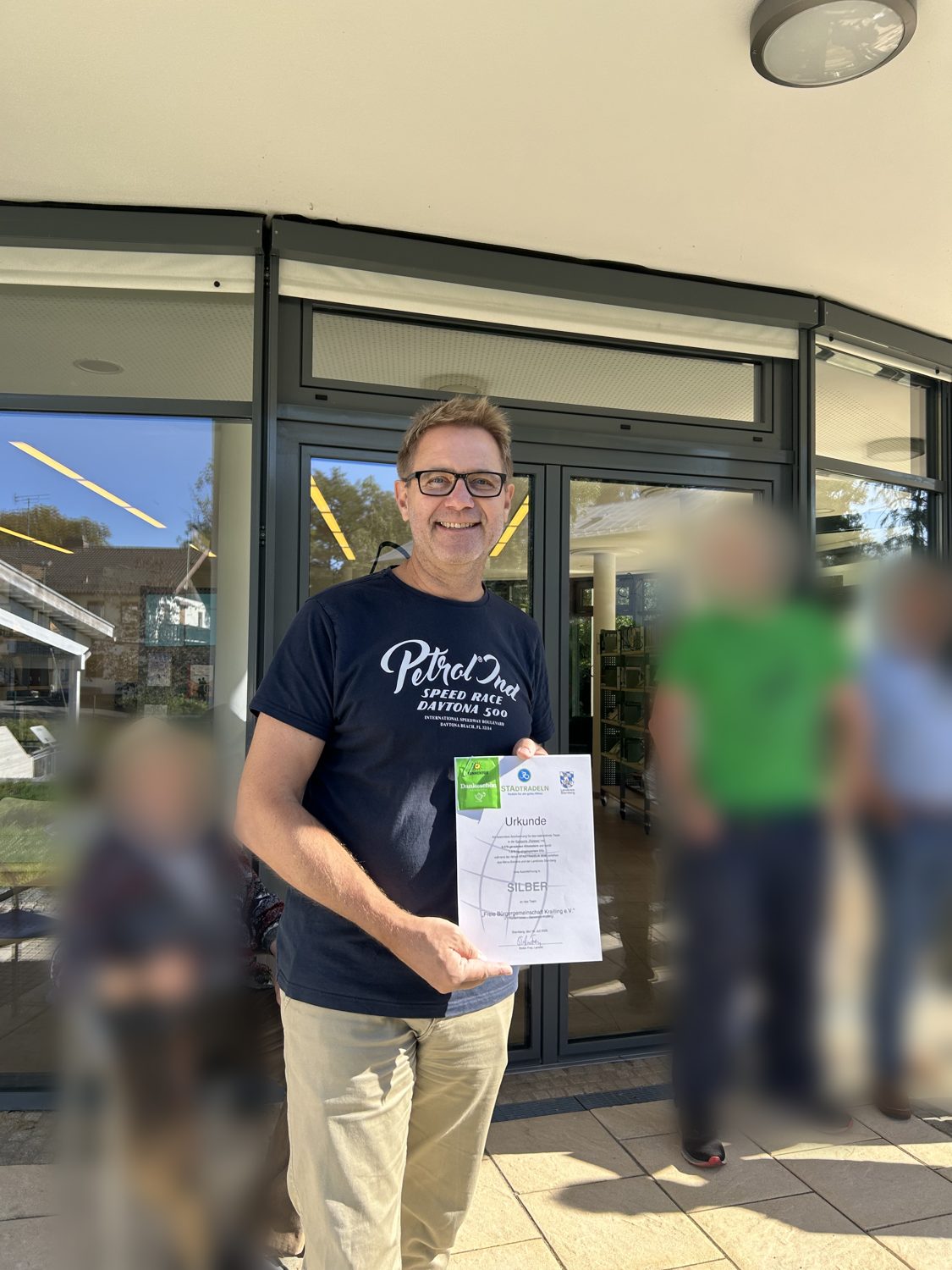 Christian Koch, Vorsitzender der FBK, mit der STADTRADELN-Urkunde in Silber vor der Bibliothek Krailling